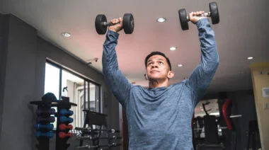 A person presses dumbbells overhead.