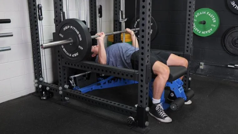 A person doing the bench press in the Barbend gym.