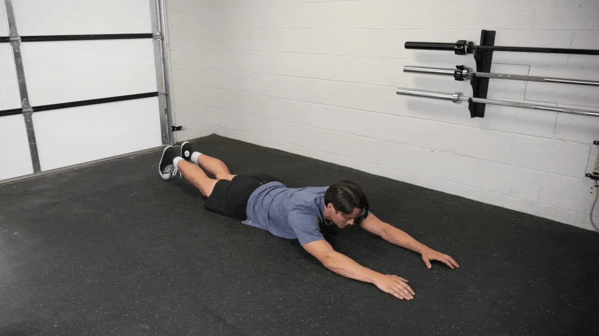 BarBend's Jake Herod performing the superman exercise for the superman workout routine.