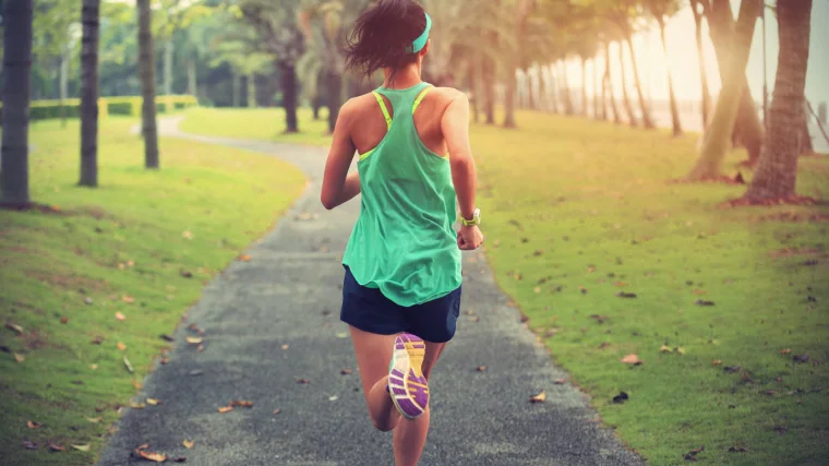 Young sports runner running on a tropical park trail.