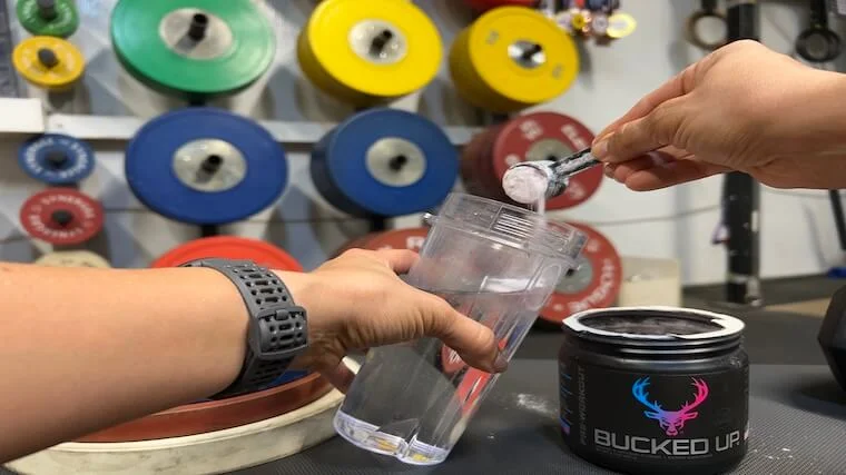 Our tester adding a scoop of Bucked Up Pre-Workout to their shaker bottle