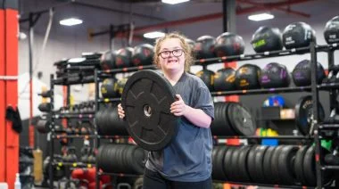 A kid holding a weight plate.
