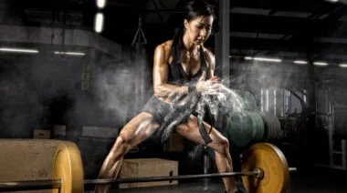 A person chalks up to prepare to deadlift.