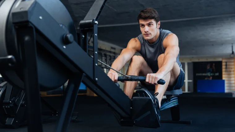 A fit person working out in the gym on a rowing machine.
