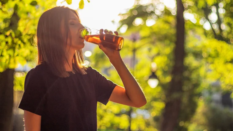 A person drinking tea from their water bottle.