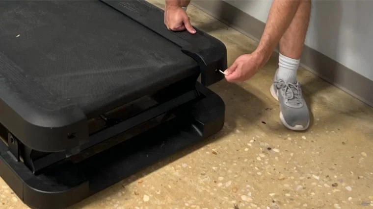A person adjusting the belt the NordicTrack X32i treadmill.