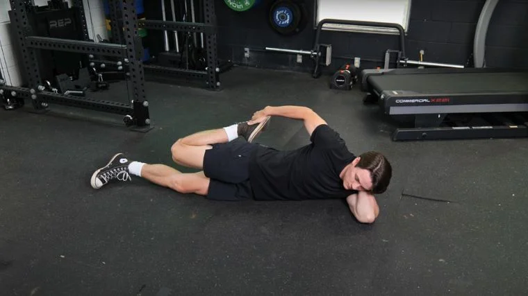 BarBend's Jake Herod performing the lying quad stretch.