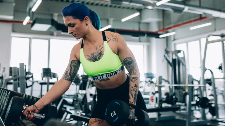 woman grabs 20 pound dumbbells off rack 