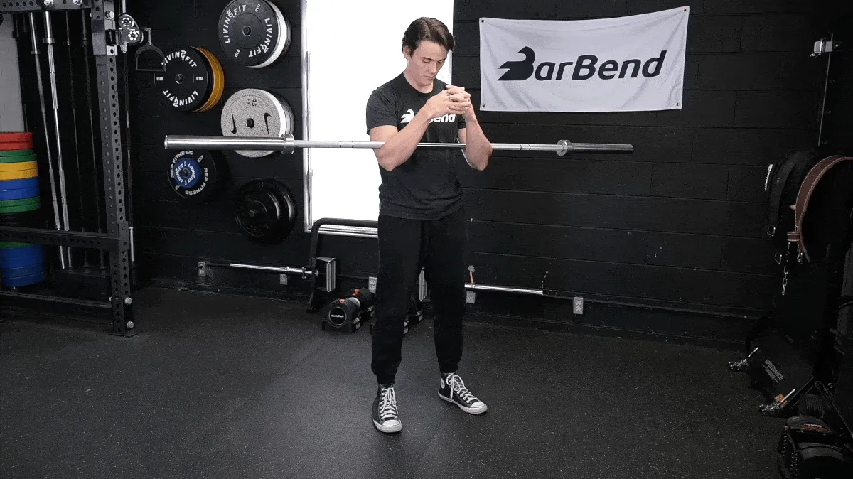 A fit person performing the barbell zercher excercise.