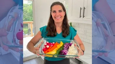 A person holds a tray of rainbow-colored foods