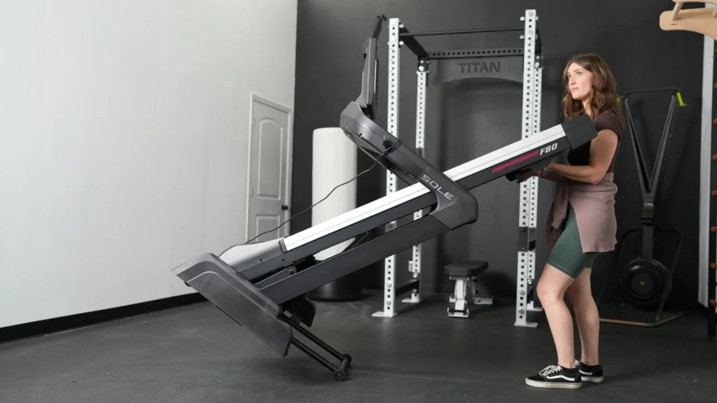 A woman moving a Sole F80 Unfolding Treadmill