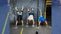 Three CfrossFit athletes doing handstands against a wall.