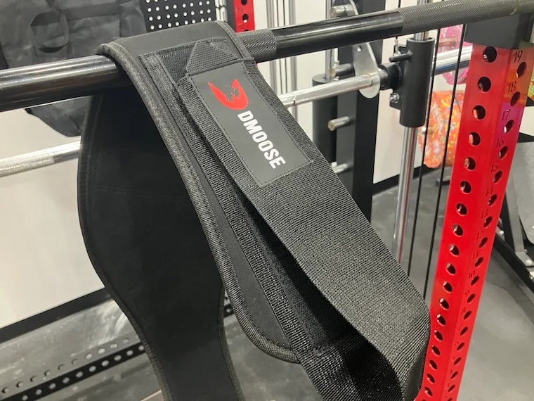 The DMoose 2-In-1 Neoprene Weightlifting Belt hanging over a barbell.