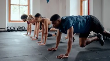 A group of athletic multiracial young adults doing mountain climbers at the gym.