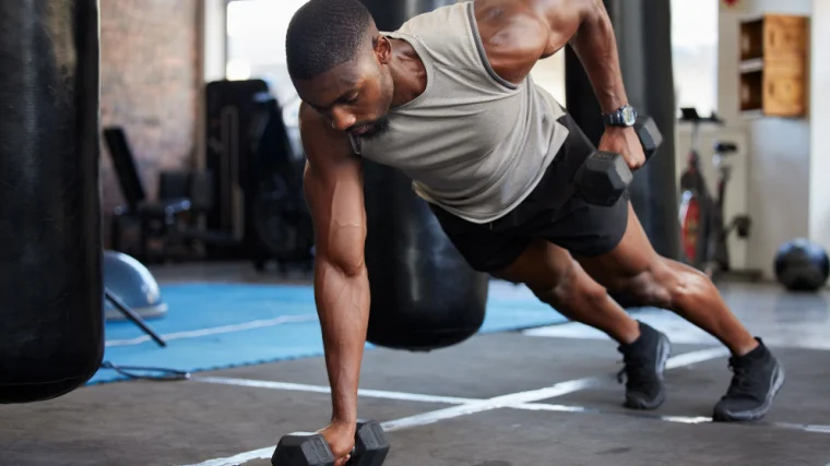A muscular person doing the renegade row. 