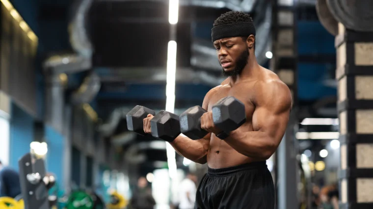 A person carrying two dumbbells with both hands at the gym.
