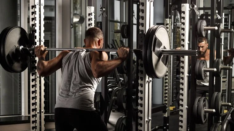 A bodybuilder using a power rack.