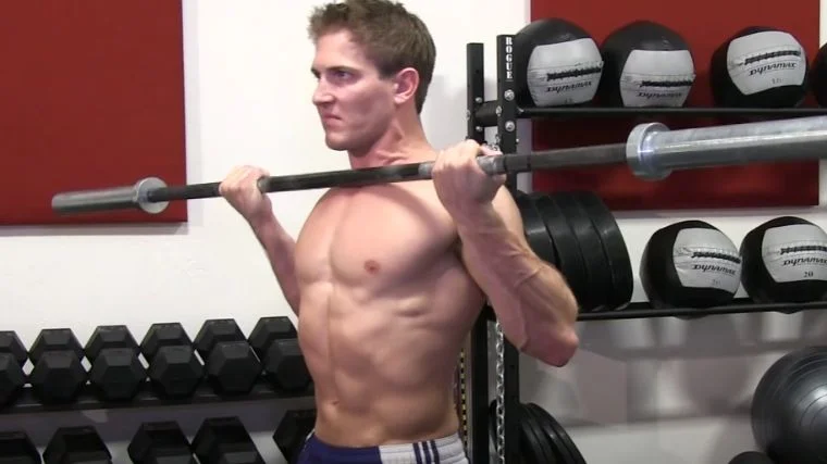 A bodybuilder completing a rep of drag curls.