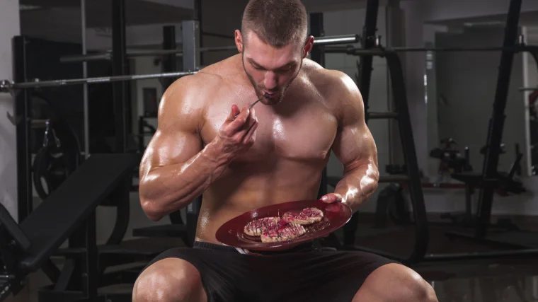 A muscular  person  eating in the gym.