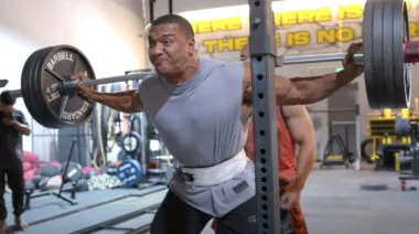 A powerlifter in a gray shirt squatting in the gym.