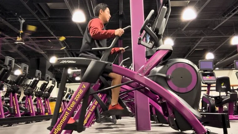 A person on an Arc trainer in a fitness center.