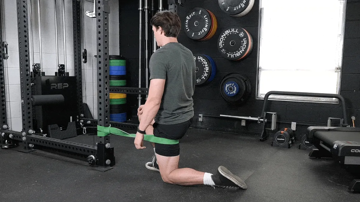 A person doing the banded hip mobilization movement. 
