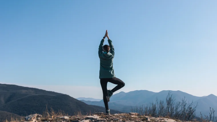 A person atop of the mountain performing a yoga mountain pose.