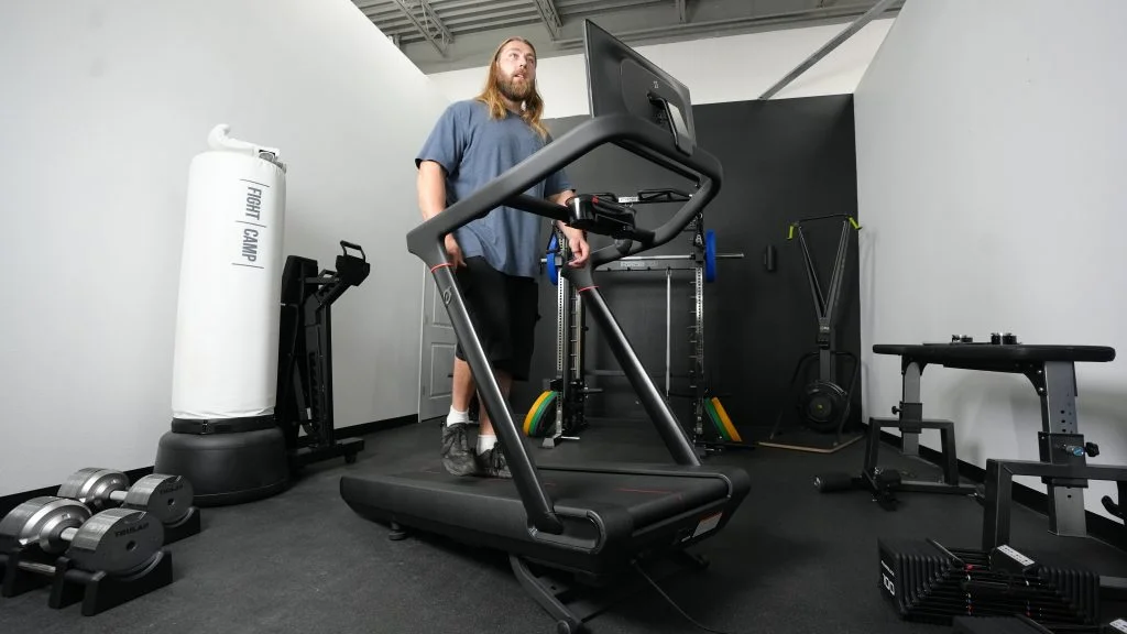 A BarBend tester walks at an incline with the Peloton Tread treadmill.