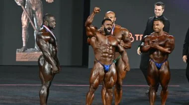 2022 Olympia Winner Hadi Choopan raises his hand on stage and roars.