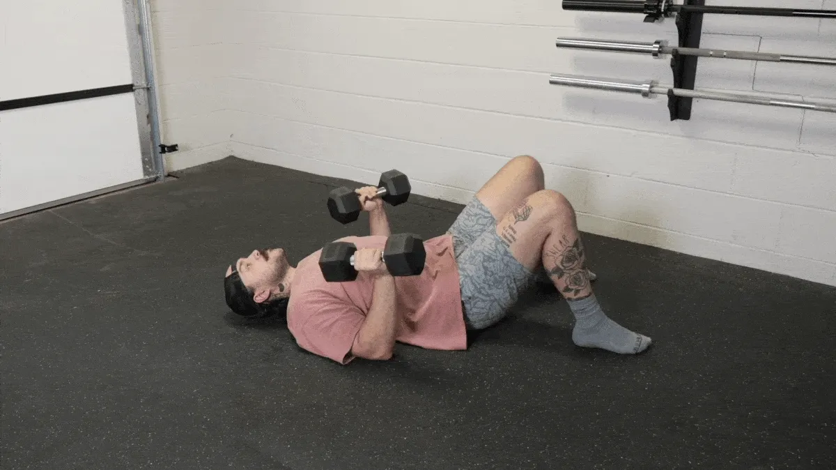 BarBend's Cooper Dennett performing the dumbbell hip extension floor press.