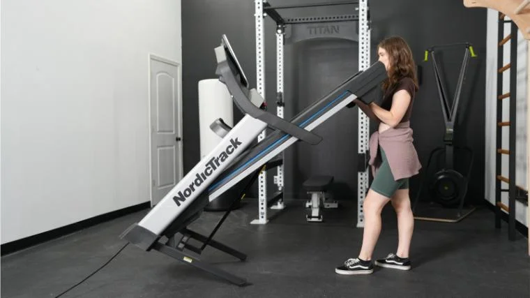 Our BarBend product tester unfolding the NordicTrack EXP 7i Treadmill.