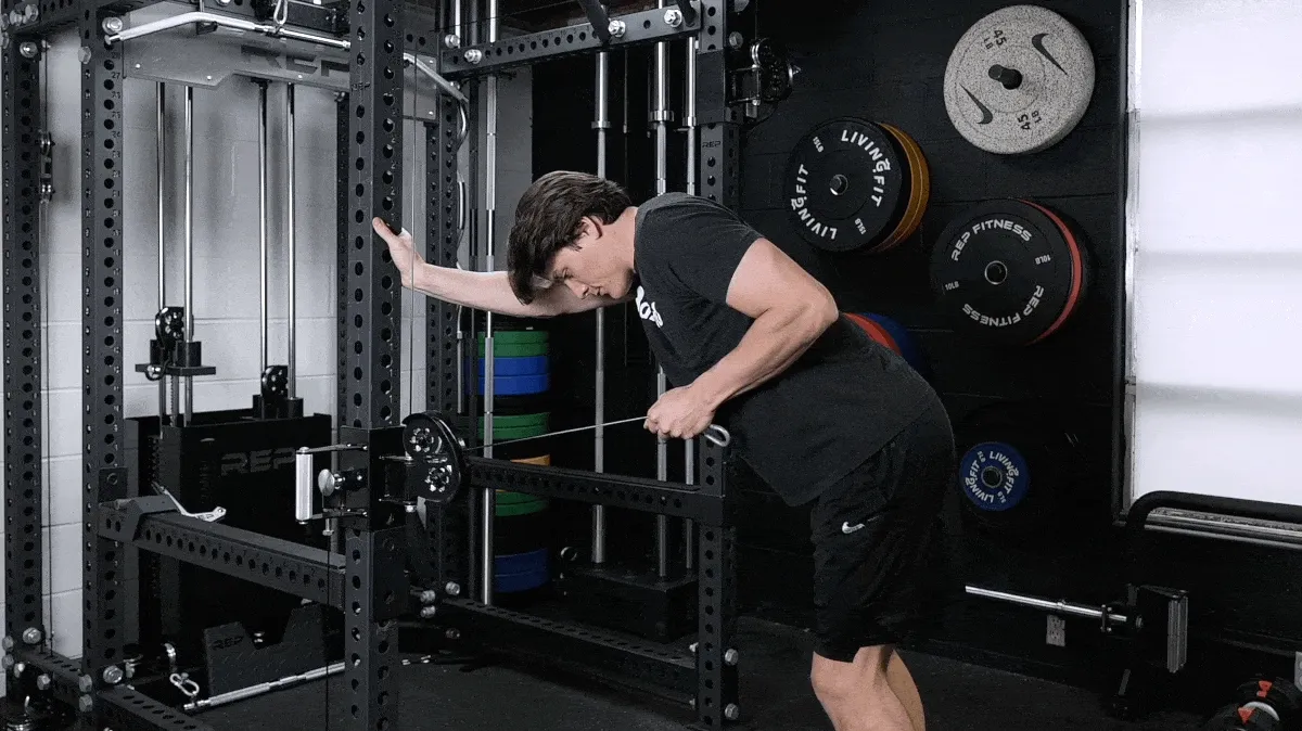A person performing the tricep cable kickback exercise.