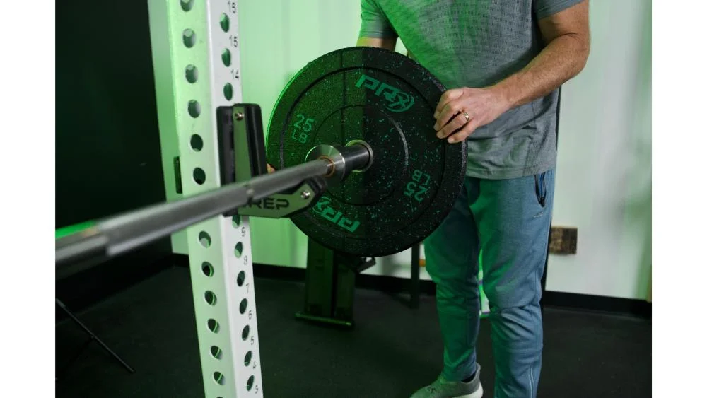 prx-crumb-bumper-plates-putting-black-and-green-plate-on-barbell-inside-view Loading PRx Crumb Rubber bumper plate on barbell
