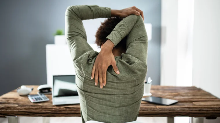A person stretching her arms at work