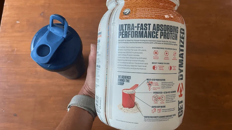 Dymatize Iso 100 container next to a shaker cup