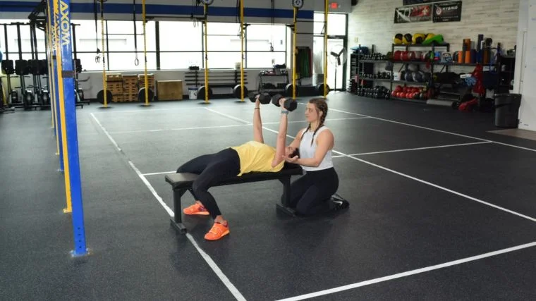 Riley Stefan spots an athlete performing the dumbbell bench press