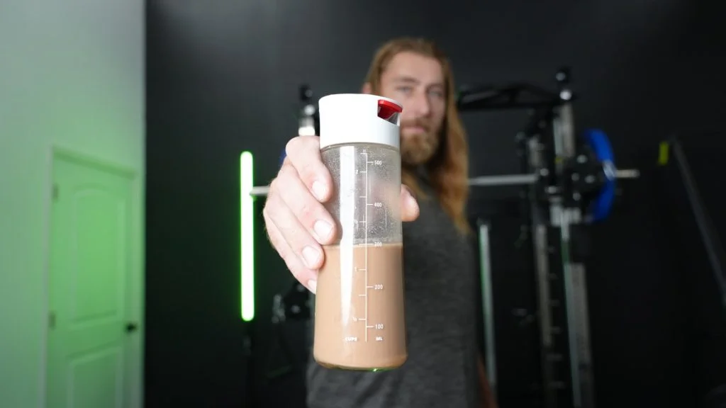 Copy of kos vegan protein powder holding bottle up