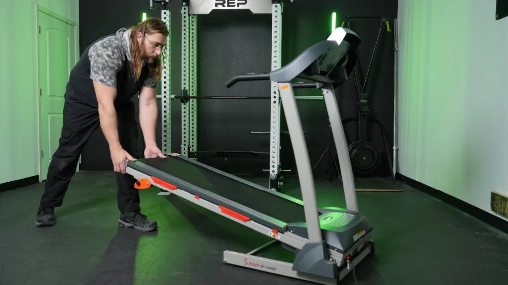 Man lowers deck from folded position on Sunny Health & Fitness TF-4400