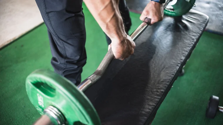 A person picks up an EZ bar with a pronated grip.