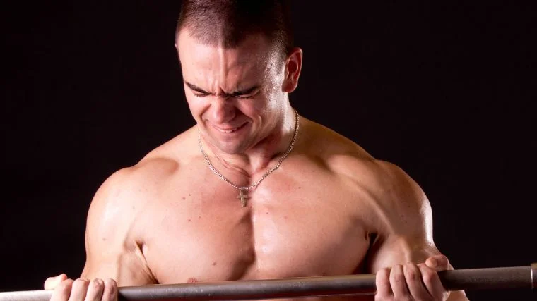A bodybuilder using heavy barbells for curls.