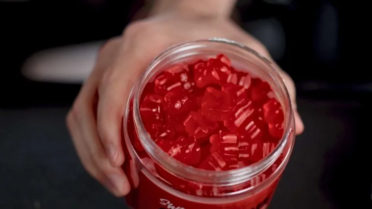 An open container held to show creatine gummies. 