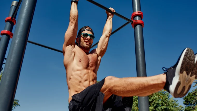 An athlete doing the hanging leg raise at an outdoor gym.