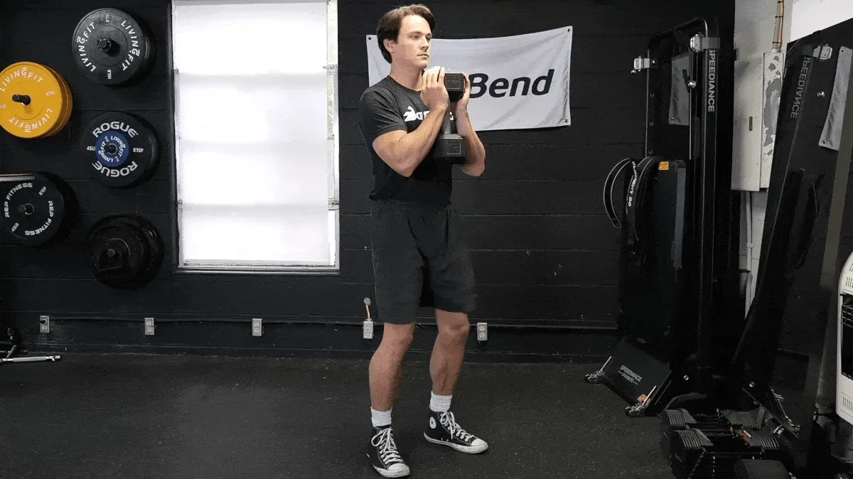 BarBend's Jake Herod performing the goblet squat exercise with a dumbbell.