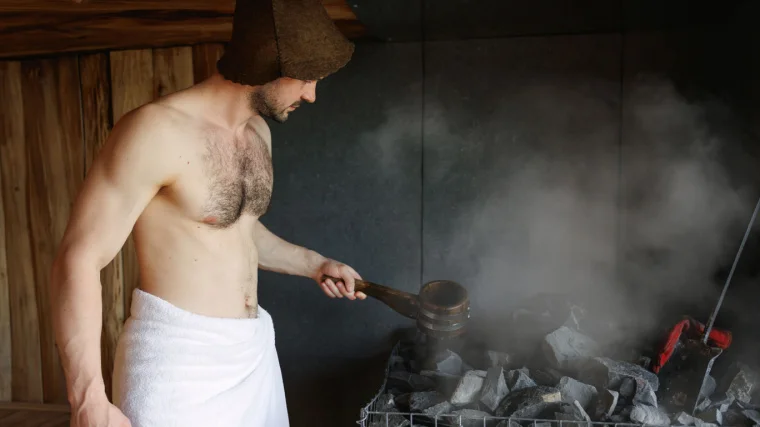 A person pouring water on hot rocks in the sauna. 