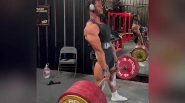 Jamal Browner stands up a 500-kilogram deadlift while wearing a belt, straps, and headphones.