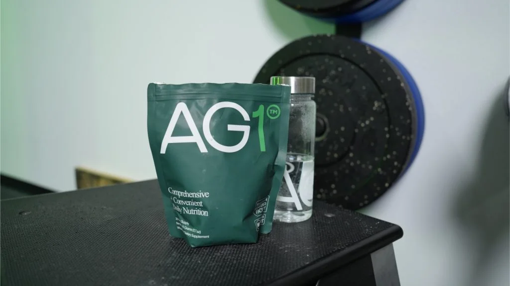A bag of AG1 Greens Powder on a bench in a gym.