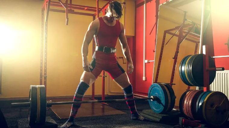Young adult athlete doing heavy sumo deadlift exercise in gym club.