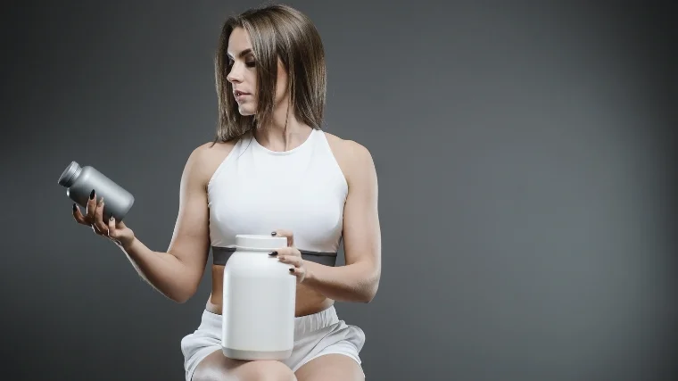 Athlete with a meal replacement shake and supplement bottles.