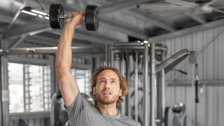 A gymgoer doing the alternating dumbbell press.