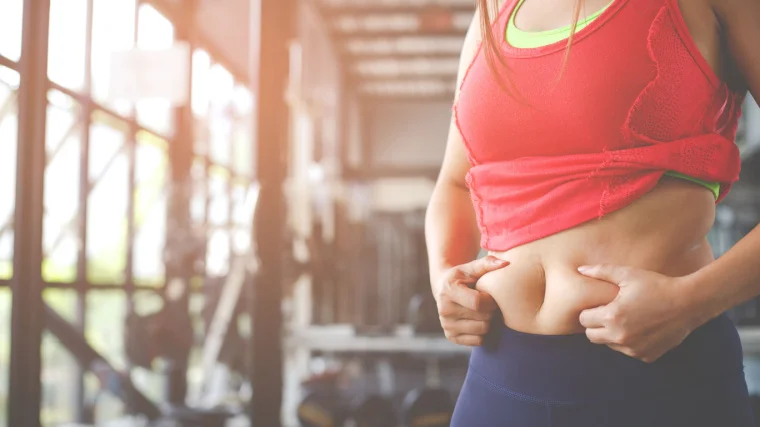A person holding their belly inside the gym.